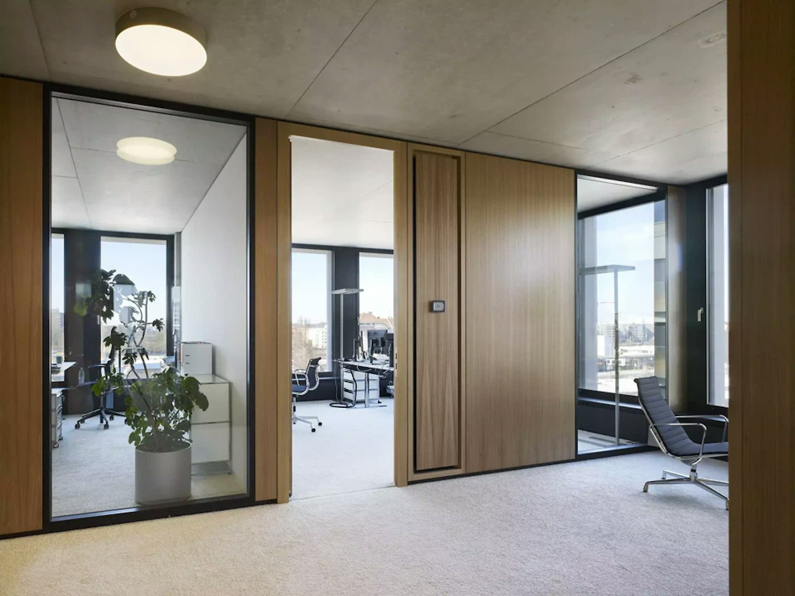 Couloir de bureaux vitré avec habillage bois et coin salon dans l'immeuble du Hamburger Bahnhof à Berlin