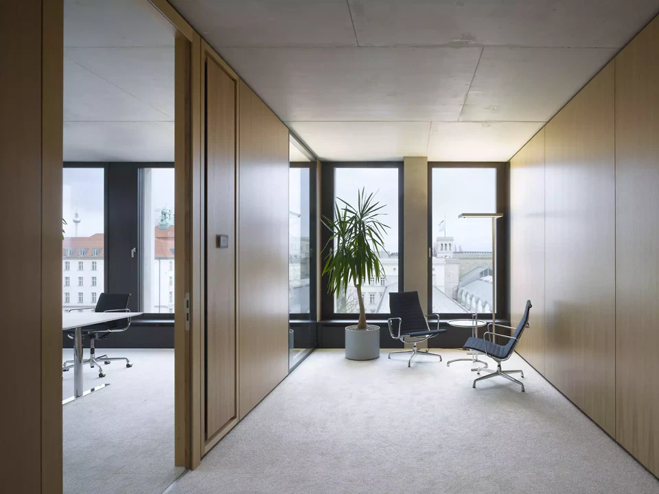 Office corner with wood panelling, lounge chairs and city views in the building at Hamburger Bahnhof, Berlin