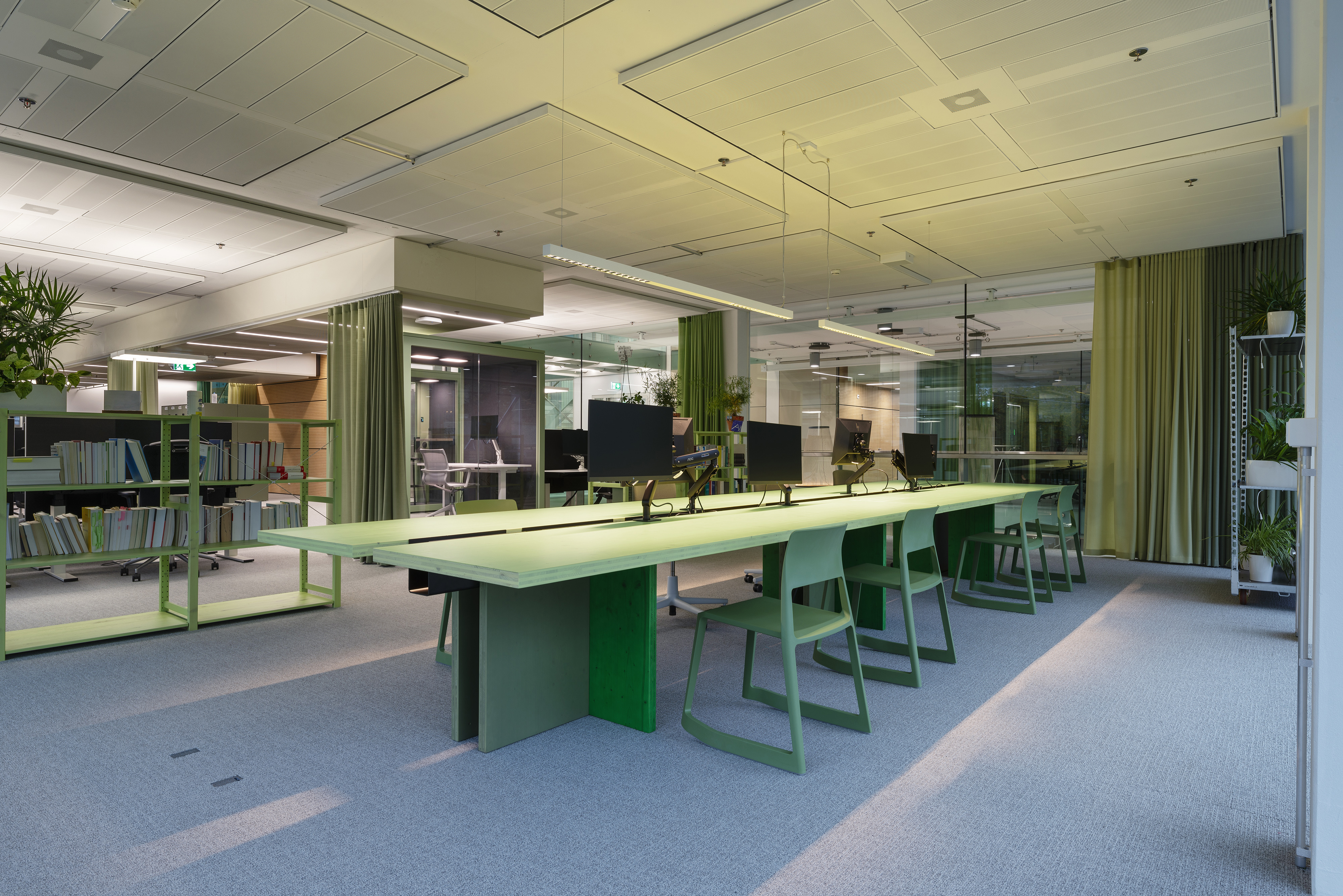Grün gestalteter Grossraumbüro-Bereich bei AXA XL Zürich mit langem Konferenztisch und Bücherregal
