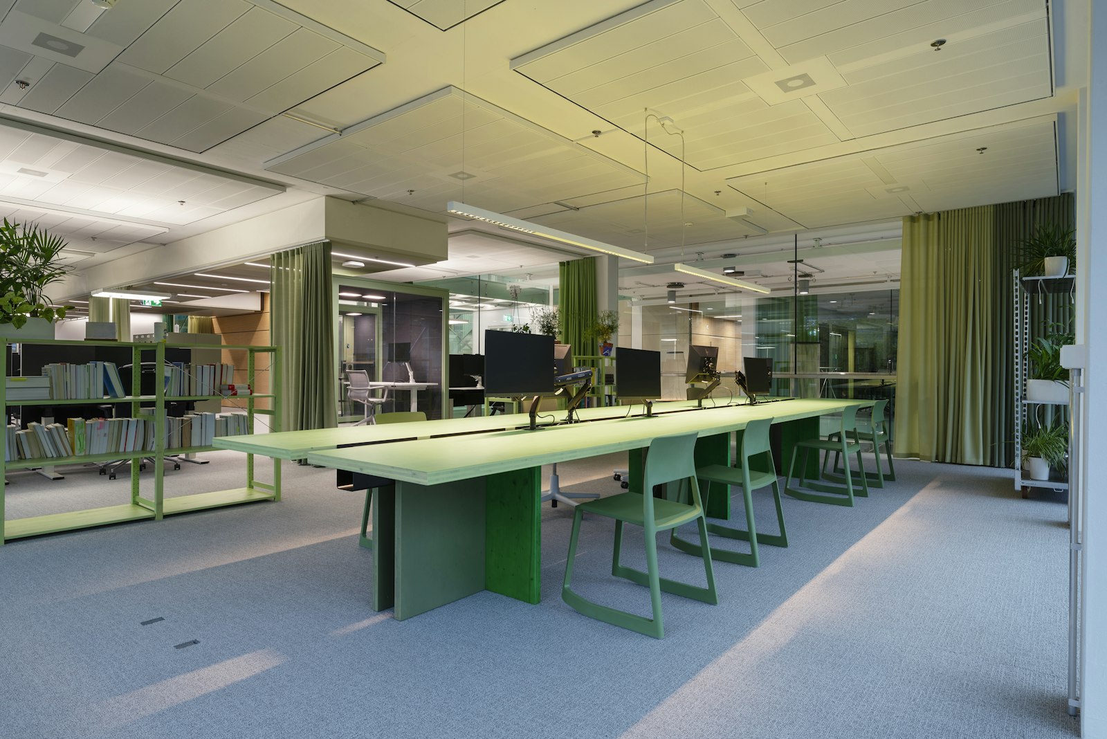 Green-toned open-plan office area at AXA XL Zurich with a long conference table and bookshelf