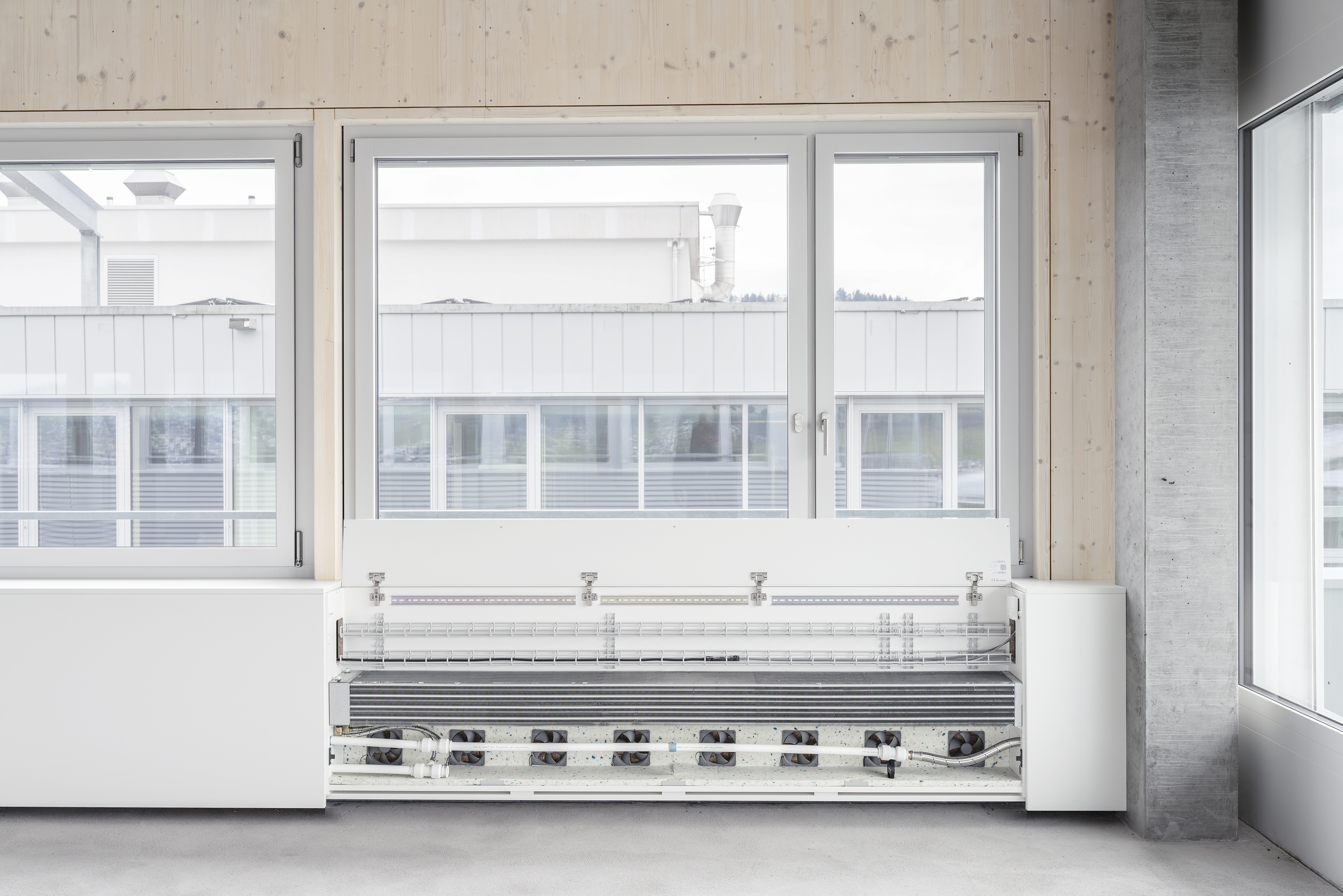 Riotherm CONVEC Klimagerät unter einer Fensterfront, Frontblende geöffnet mit sichtbaren Ventilatoren