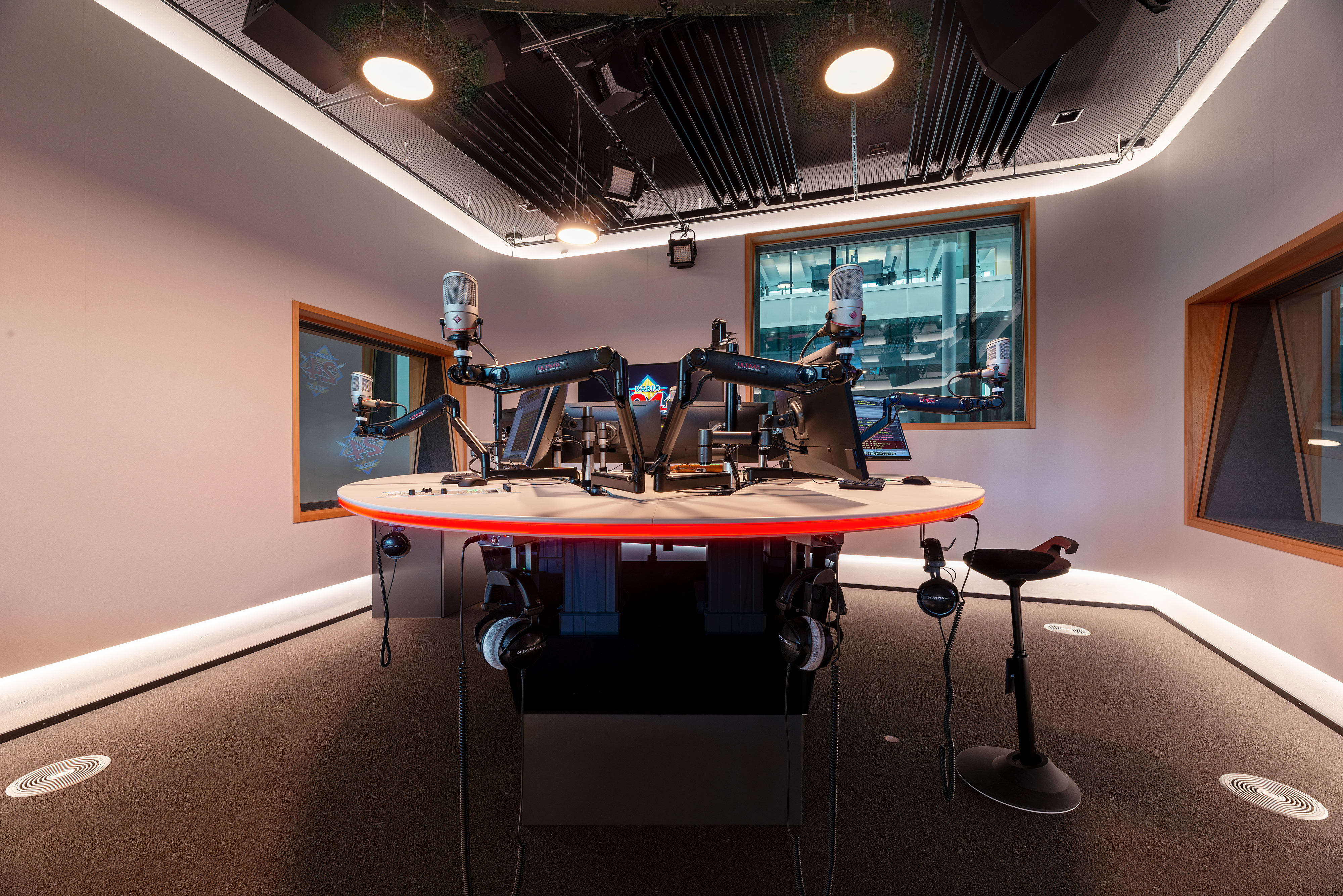 Round broadcast desk with multiple microphone arms and red LED lighting in the CH Media radio studio Zurich