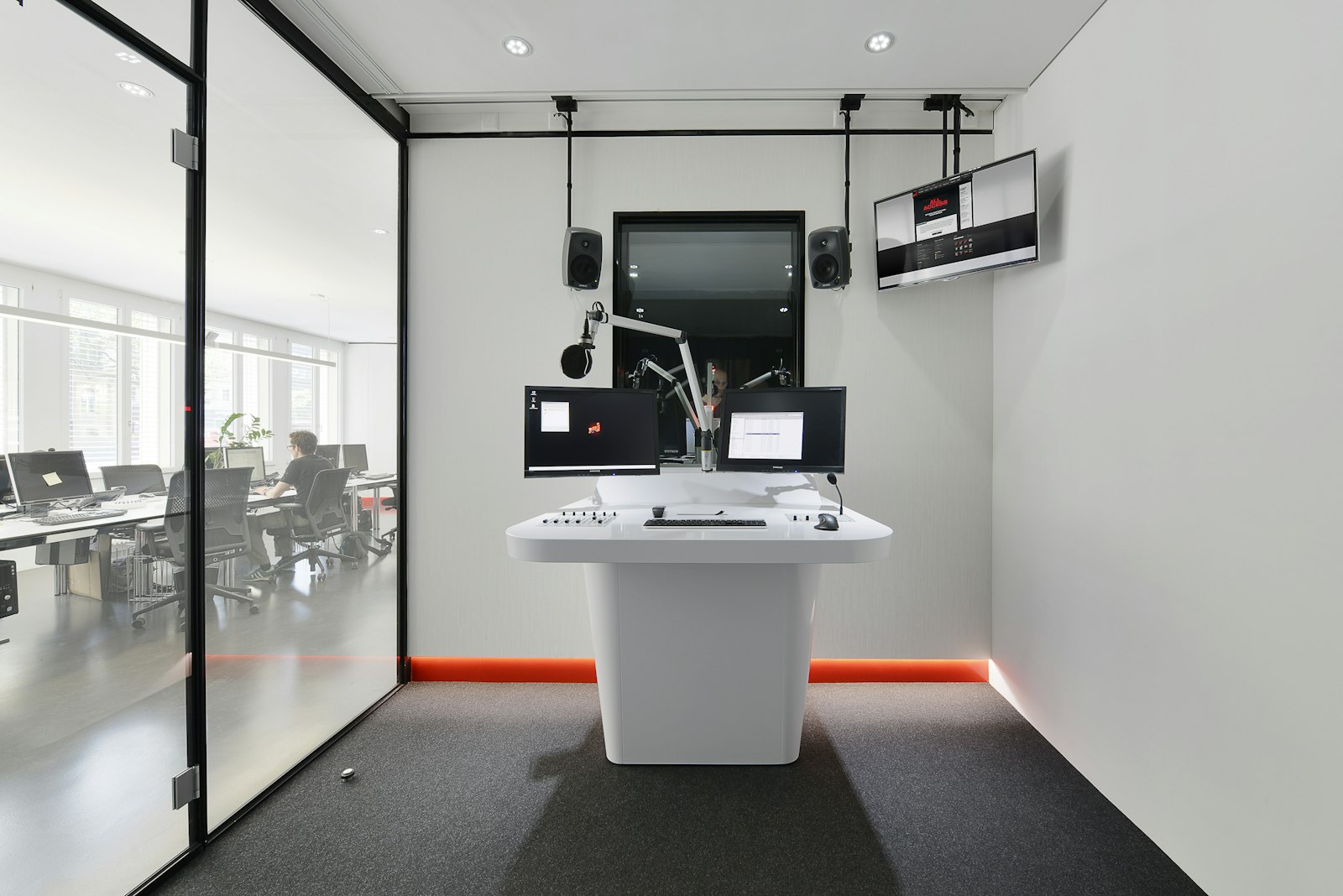 Weisser Moderationstisch mit roter LED-Lichtleiste und Bildschirmen im Studio von Radio energy