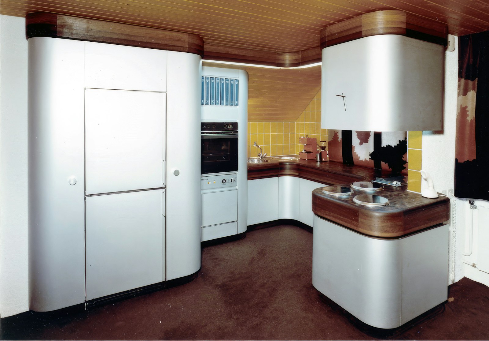 1970s fitted kitchen with curved white cabinetry and wood accents, an early Erich Keller interior