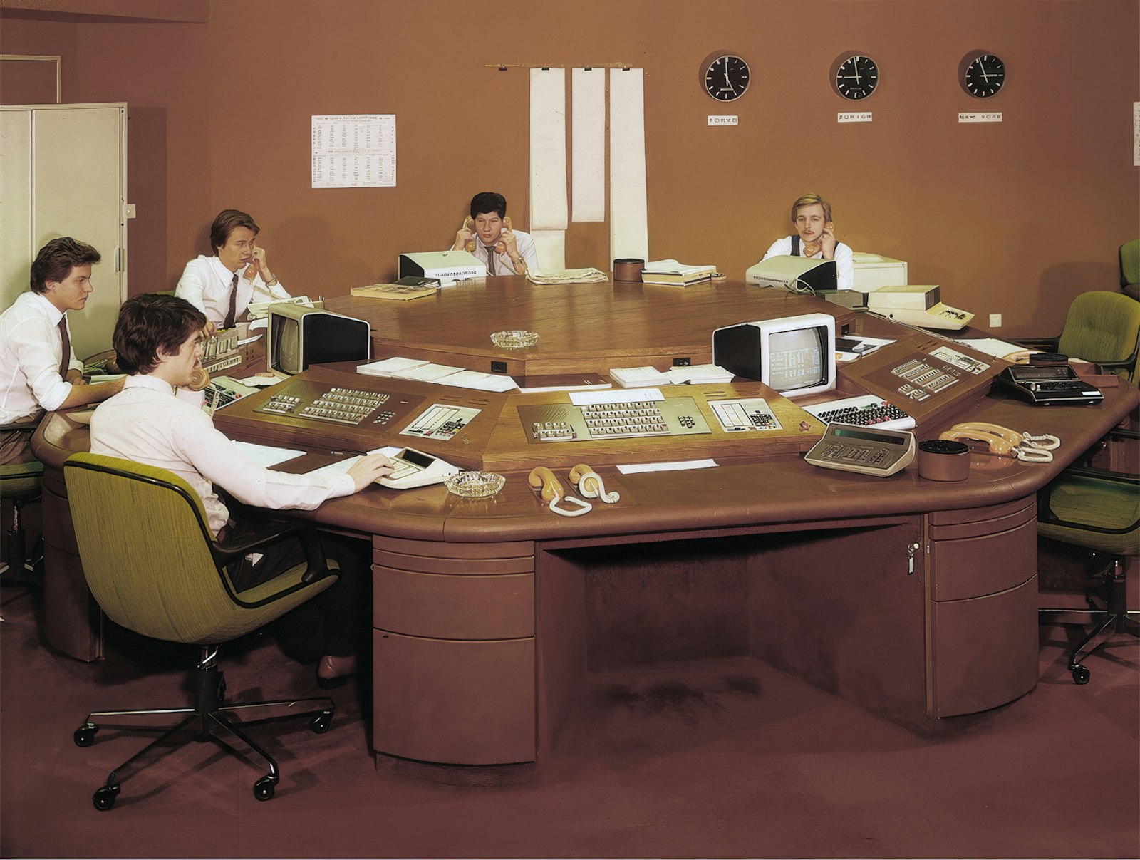 Hexagonal control desk with several workstations, monitors and world clocks, 1970s