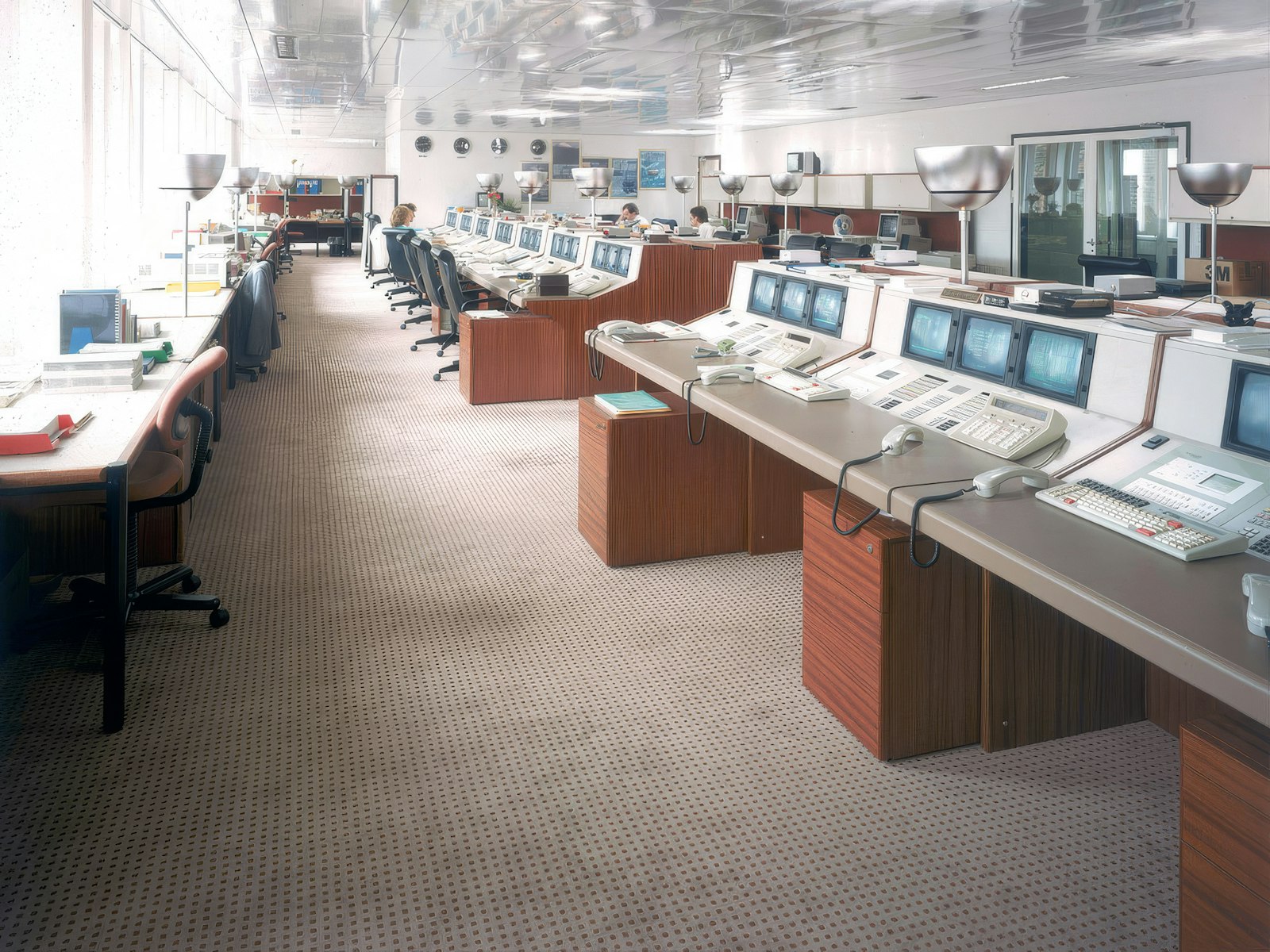 Open-plan trading floor with several rows of curved workstations and monitors