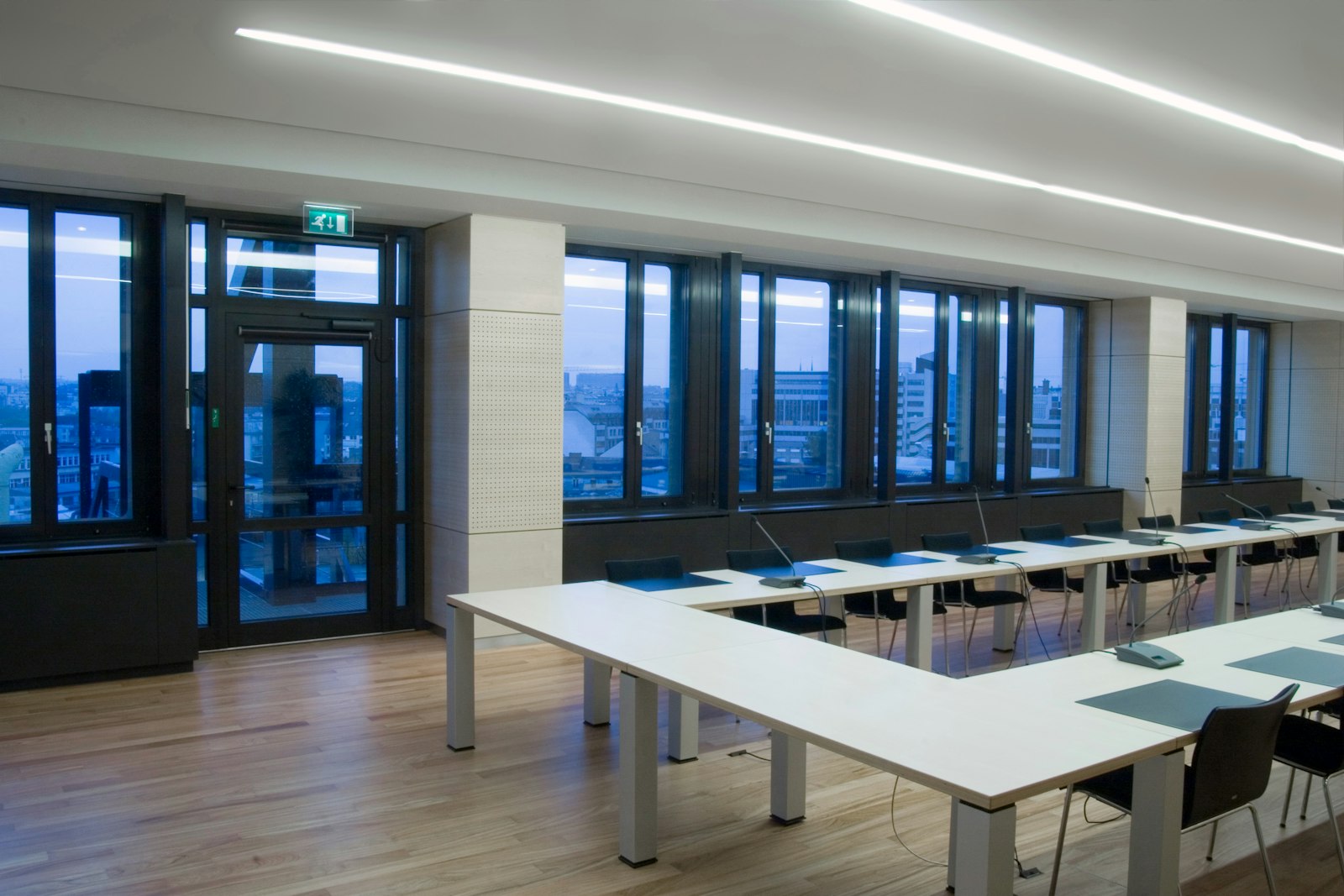 Modern boardroom with a U-shaped conference table, microphones and a city view