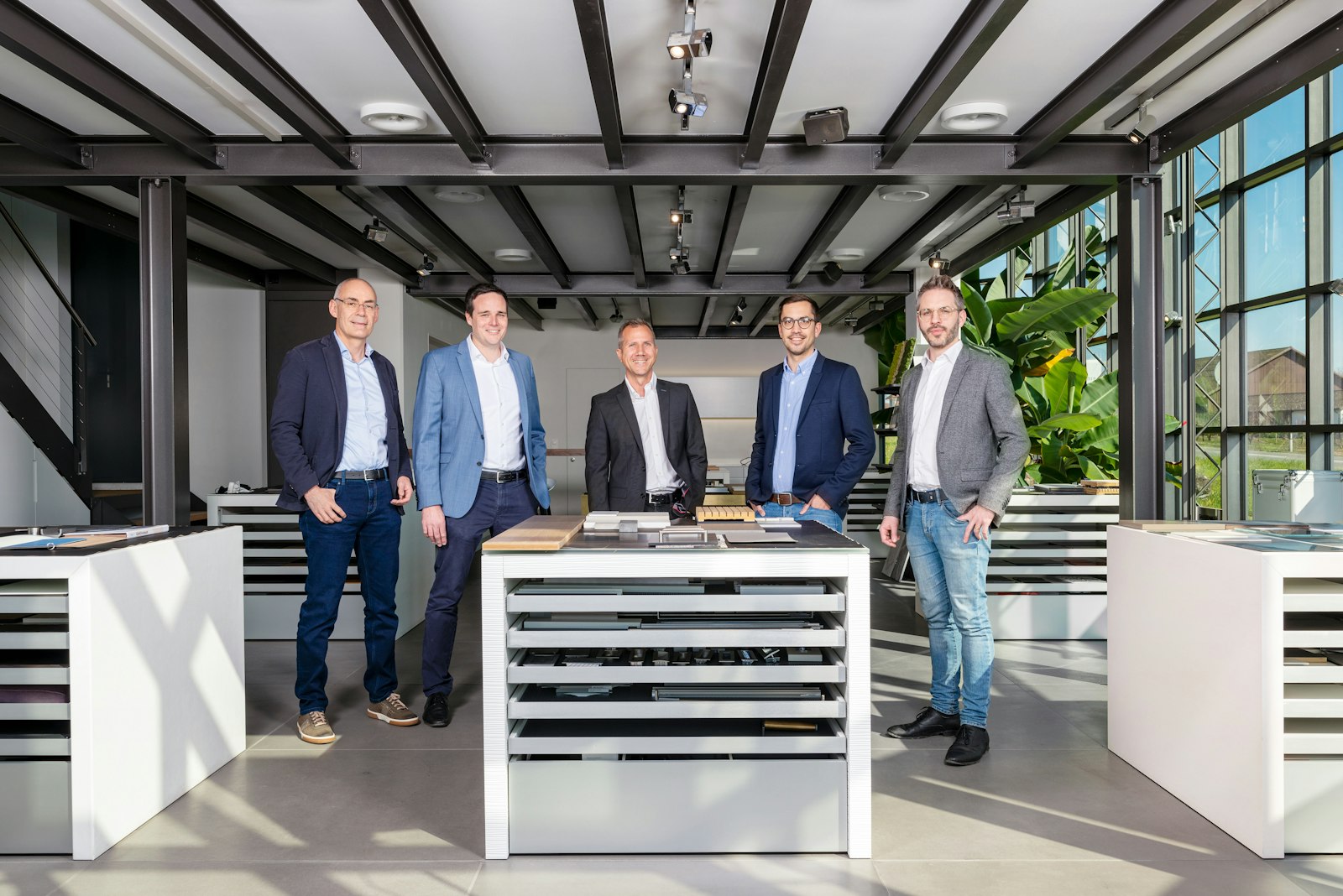 Erich Keller team members stand in the bright showroom among sample and material tables, 2021