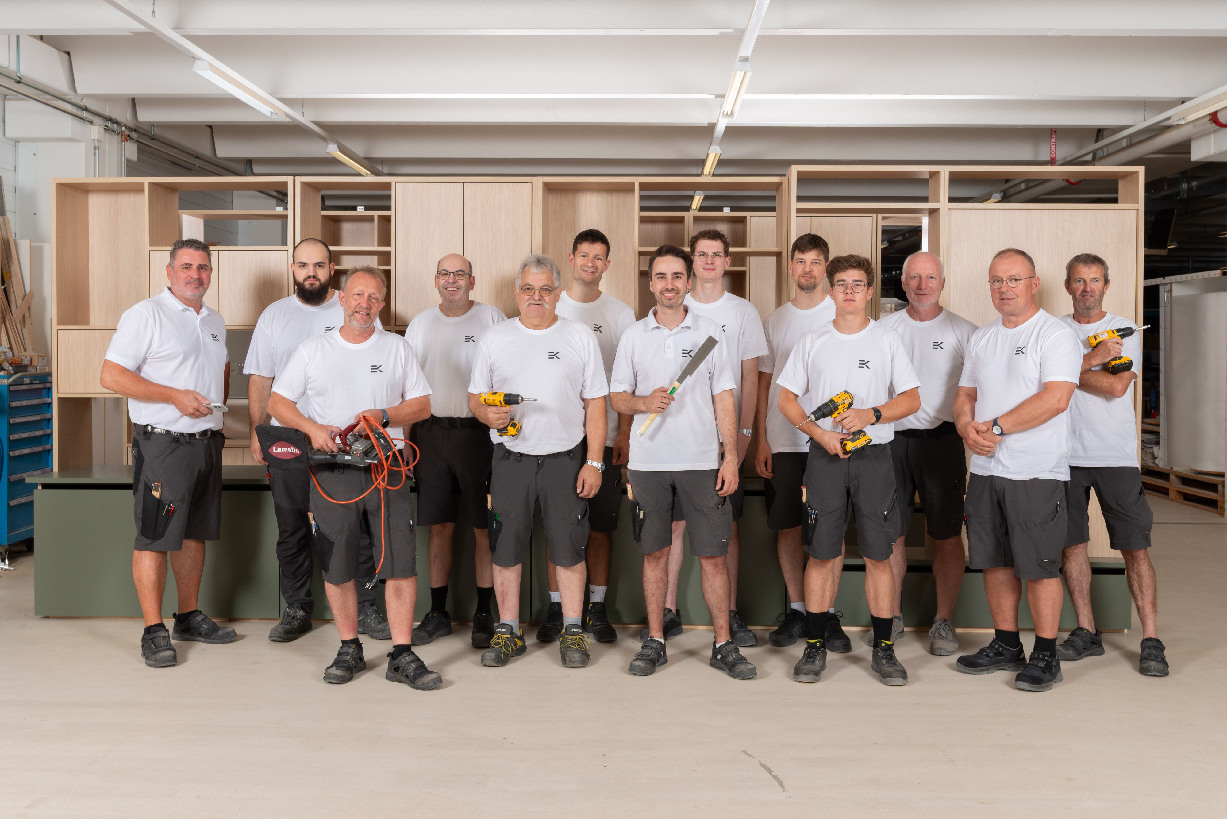 Schreinerteam der Erich Keller AG vor selbst gefertigten Holzschraenken in der Werkstatt