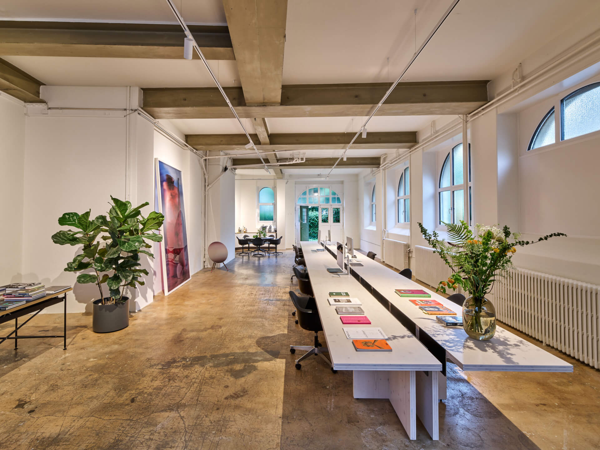 Loft-Büro mit Sichtbalken, langem Arbeitstisch und Pflanzen bei heart identity AG