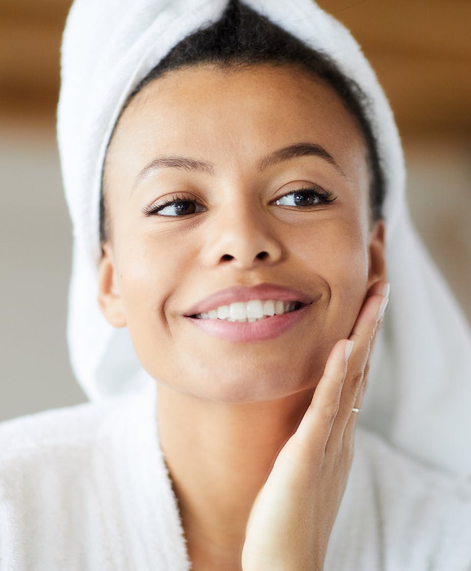 woman smiling and touching her cheek
