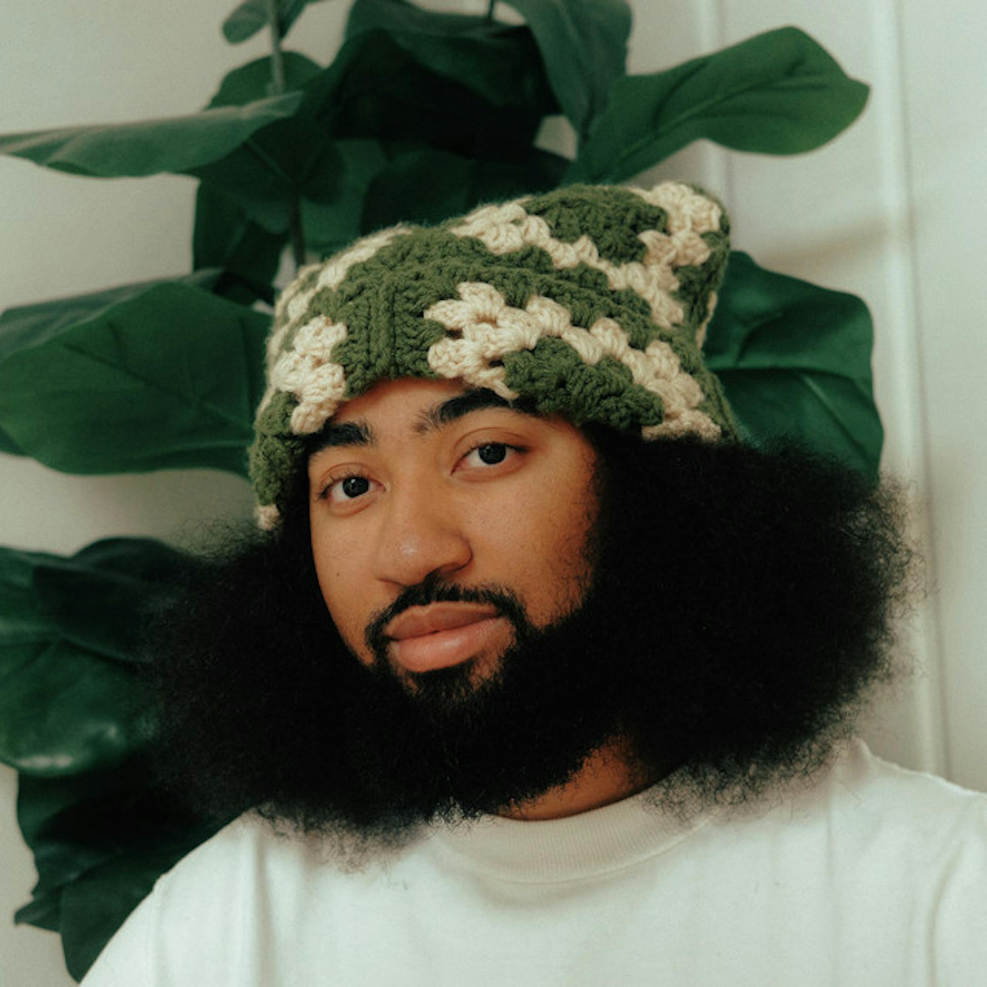 A closeup of L.Dre's face with a plant visible behind him