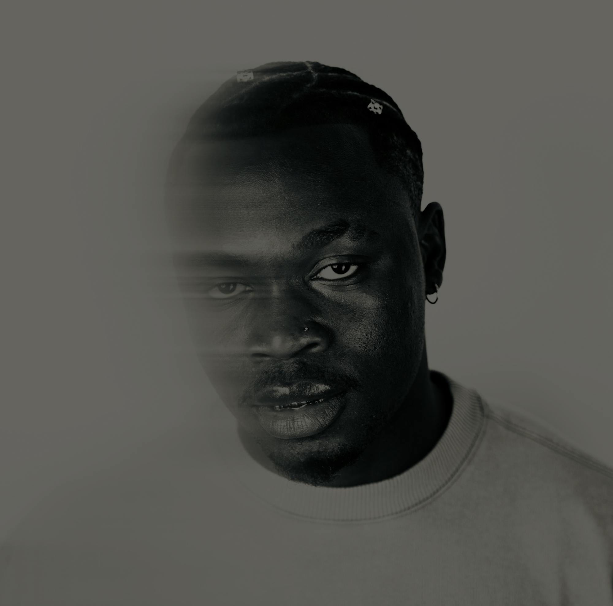 Closeup of Timi Dre's face in front of a white background. The left side of his face is slightly blurred