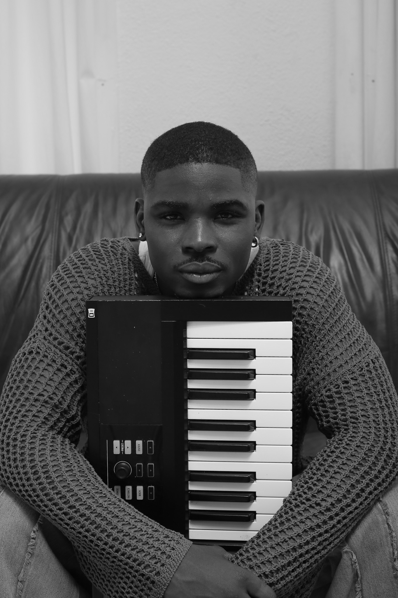 Gemaine Edwards sitting down holding a MIDI keyboard between his arms