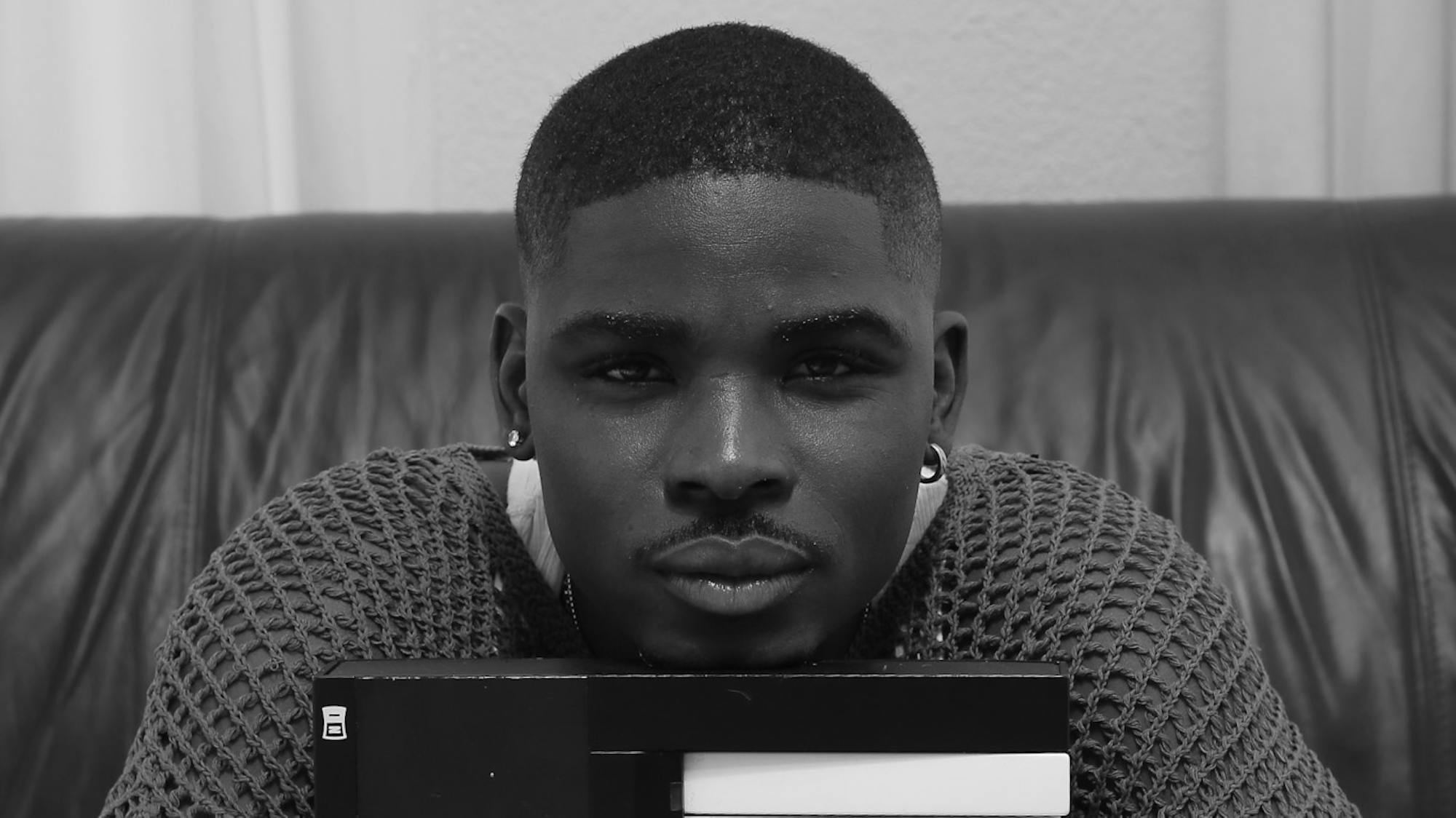 Gemaine Edwards sitting down holding a MIDI keyboard between his arms