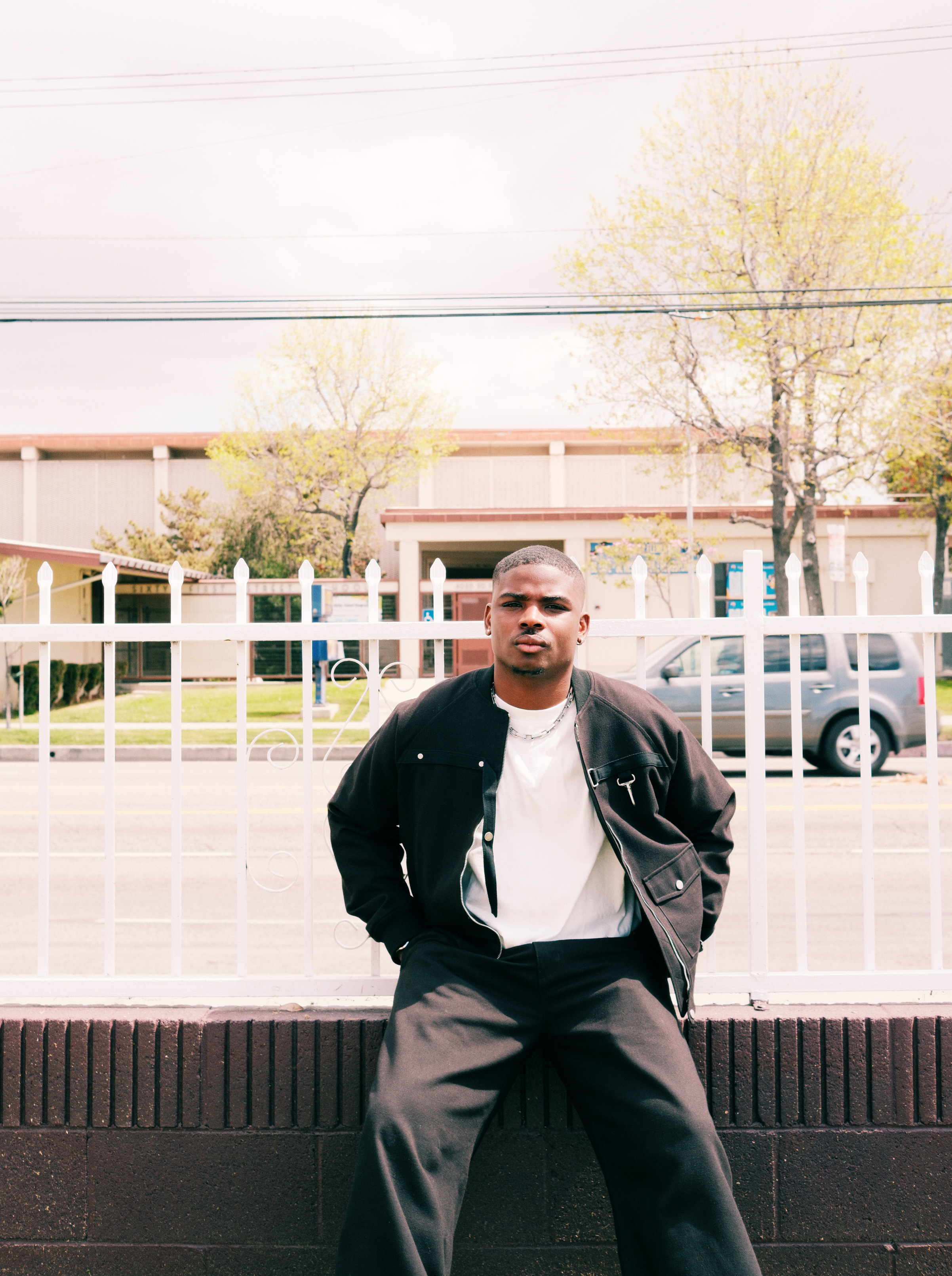 Gemaine Edwards sitting on a ledge outside in a suburban area.