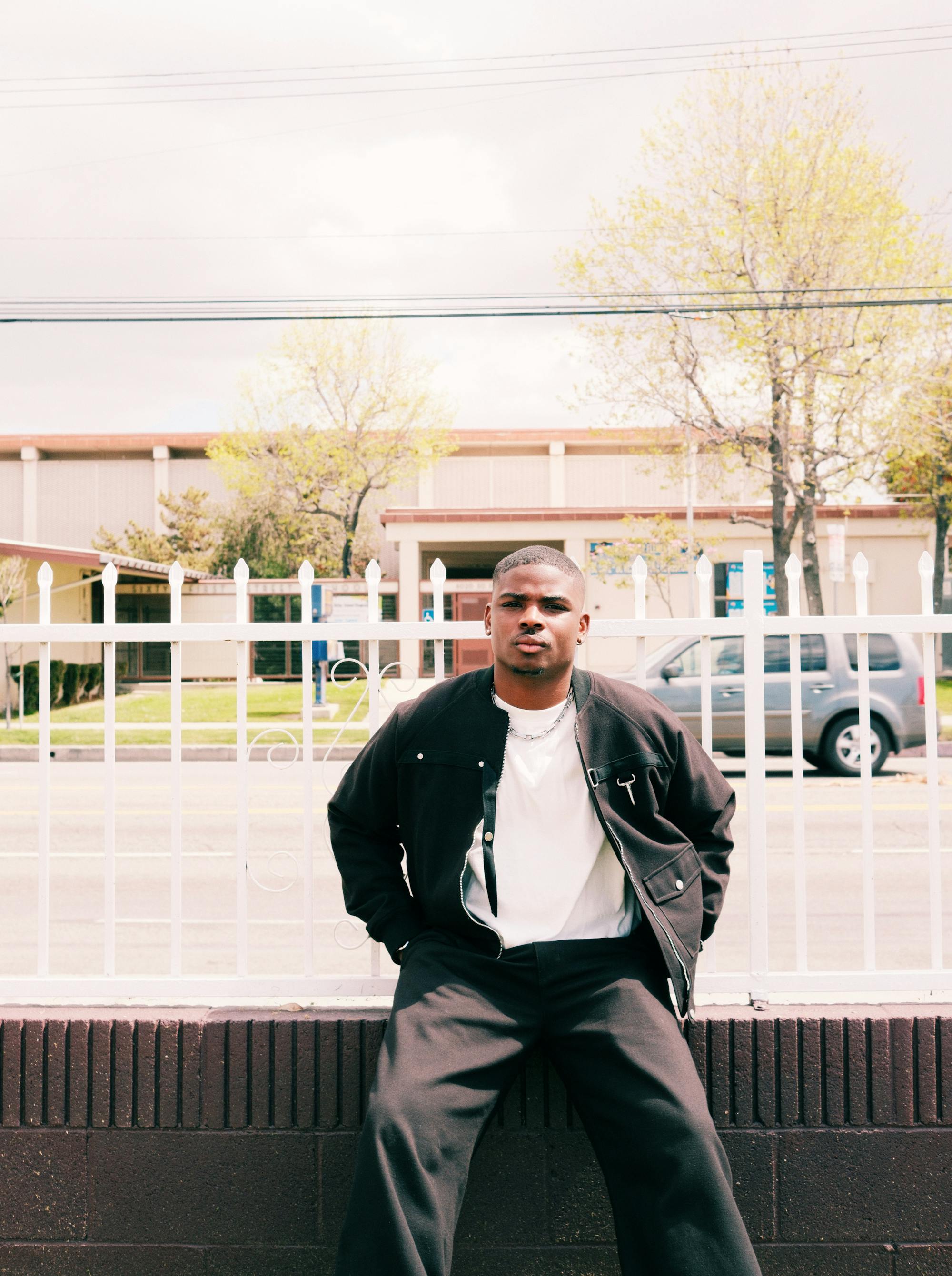 Gemaine Edwards sitting on a ledge outside in a suburban area.