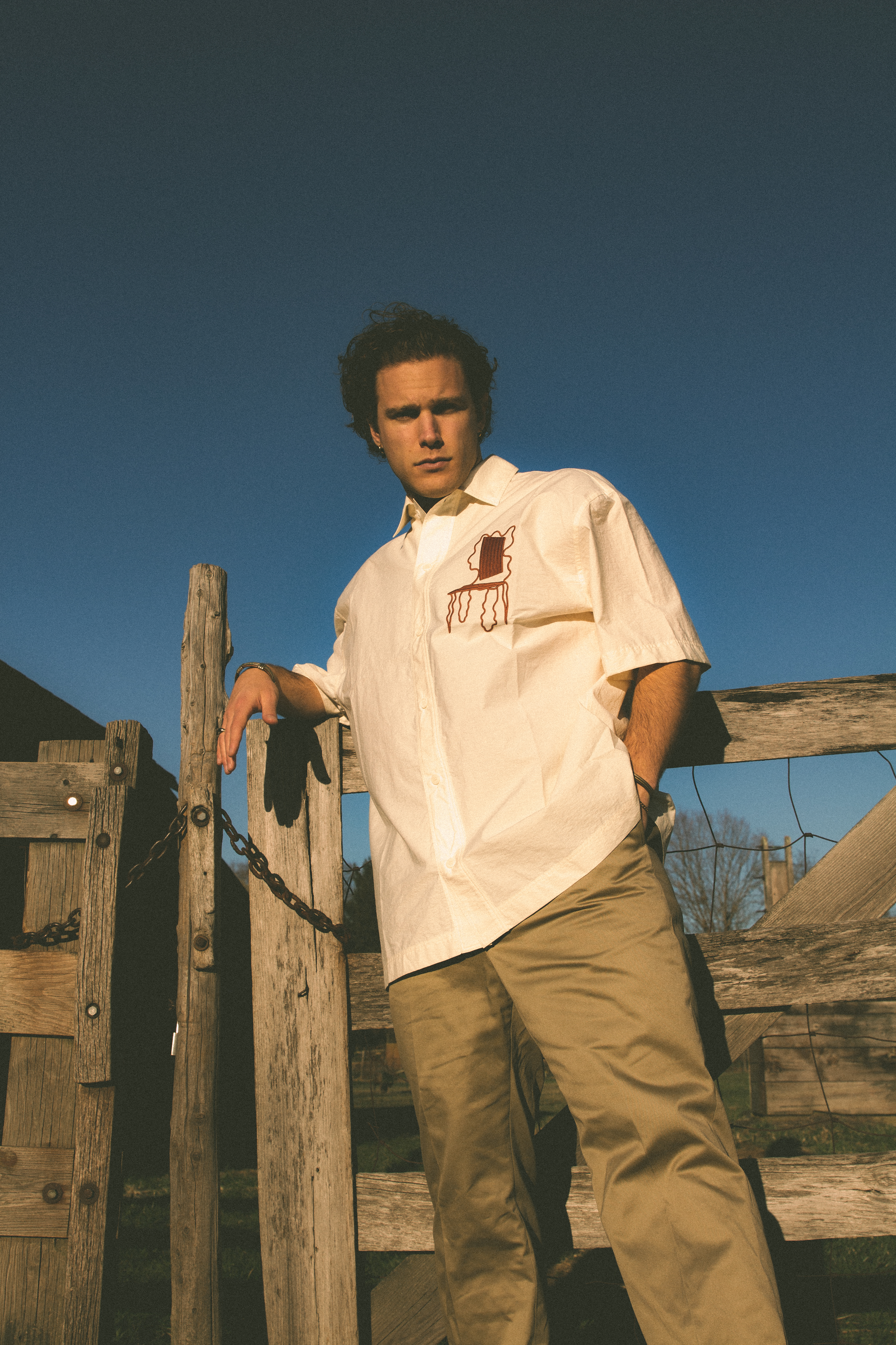 Aaron Taos standing outside in front of a wooden fence.