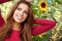 A woman smiling beside a sunflower