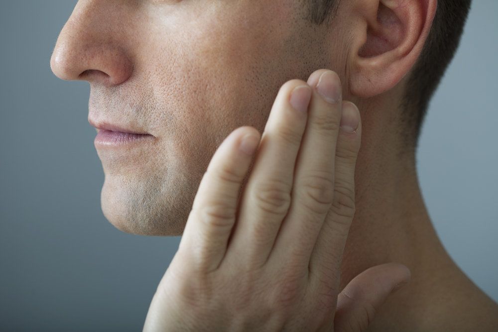 Close-up of man touching his jaw