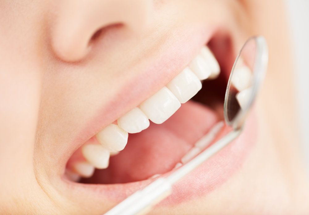 A dental mirror being held up to a mouth full of healthy, radiant teeth - thanks to preventive dentistry