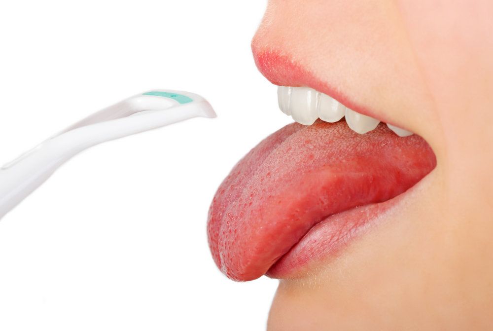 Close-up on woman scraping her tongue