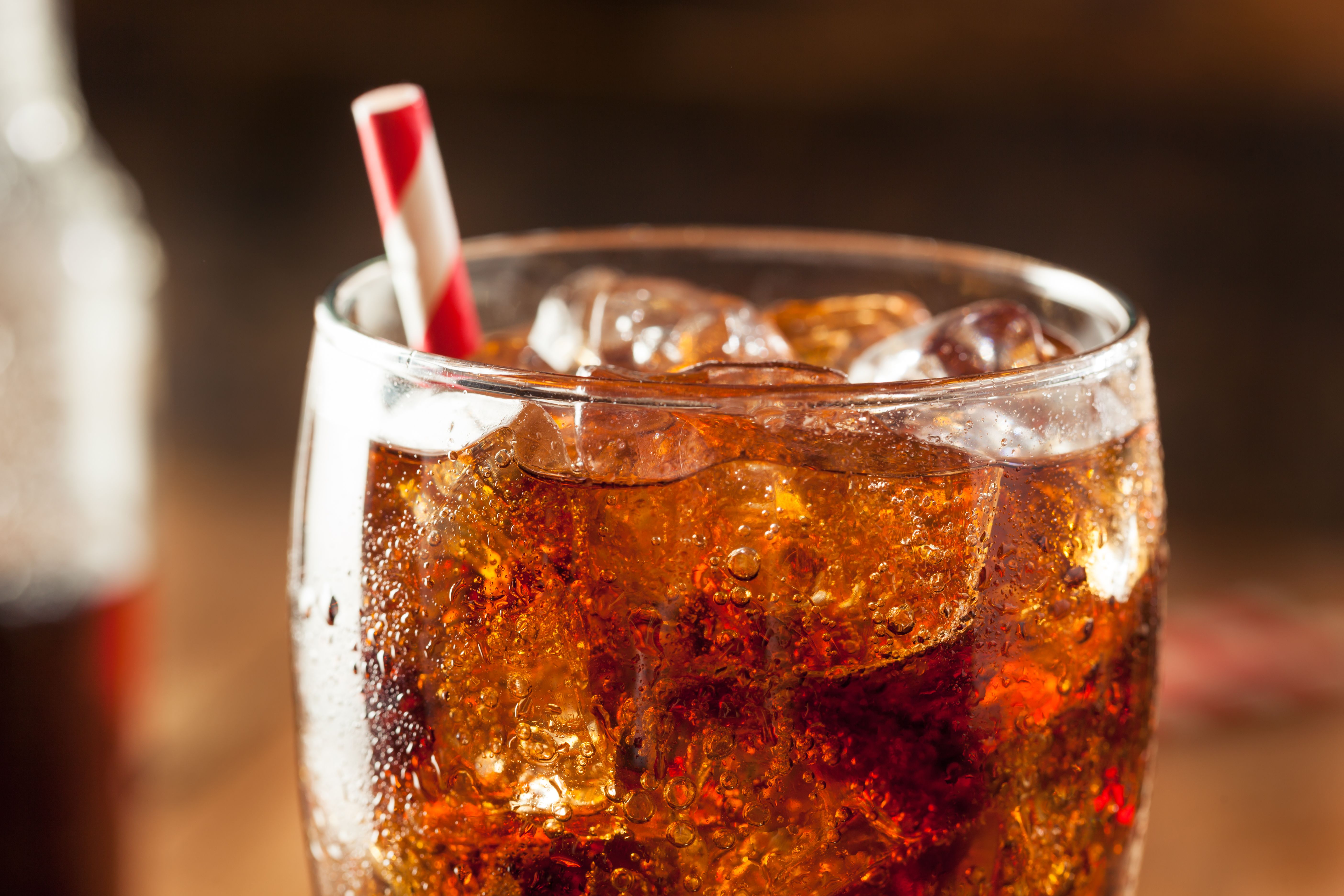 A photograph of a dark soda with a straw in it