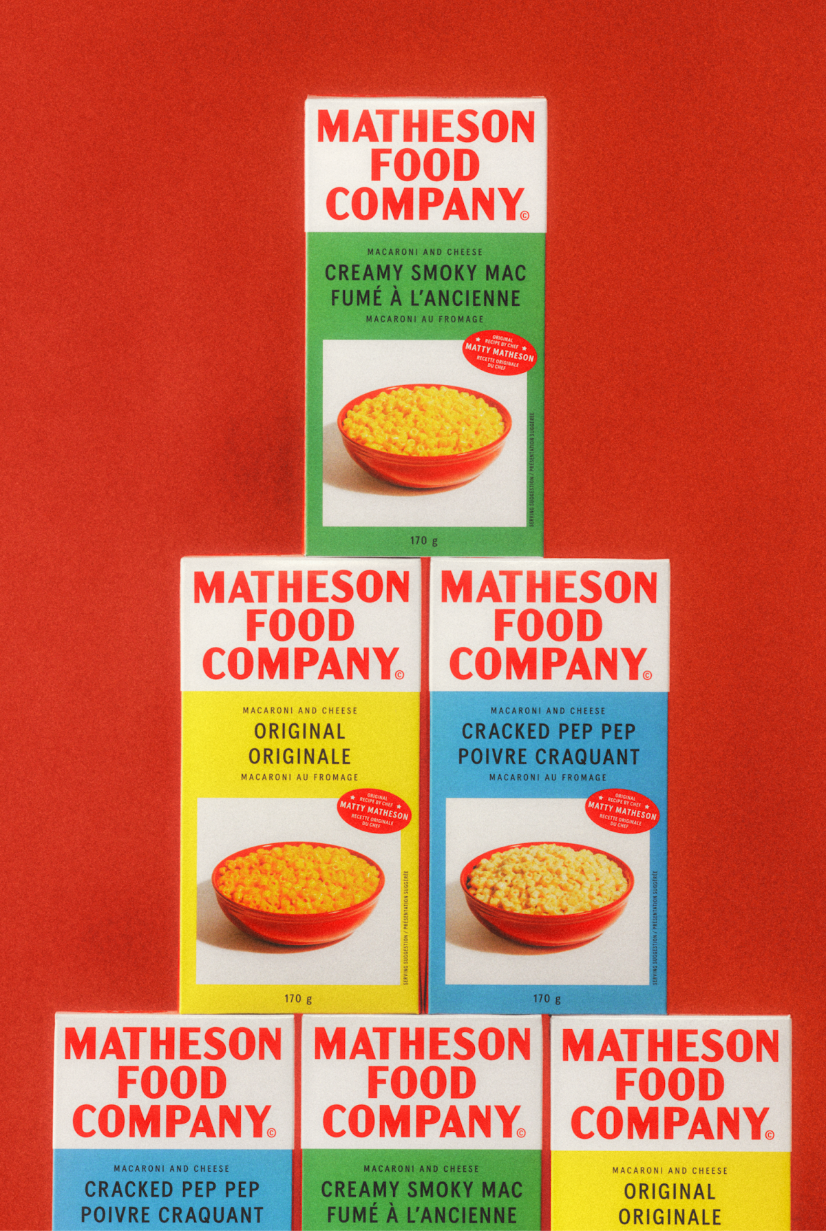 Stack of 5 boxes of Matheson Food Company mac and cheese on a red background.
