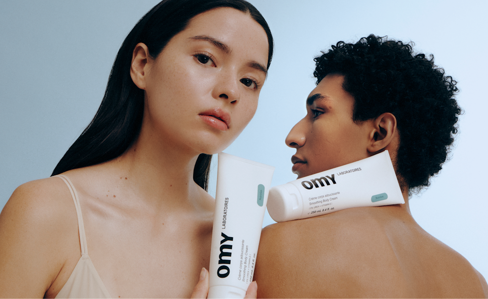 Omy Laboratoires skincare packaging presented in a minimalist campaign portrait with two models.