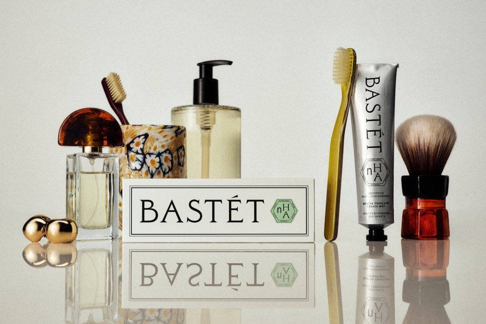 Bastét toothpaste packaging displayed among bathroom objects and grooming accessories.