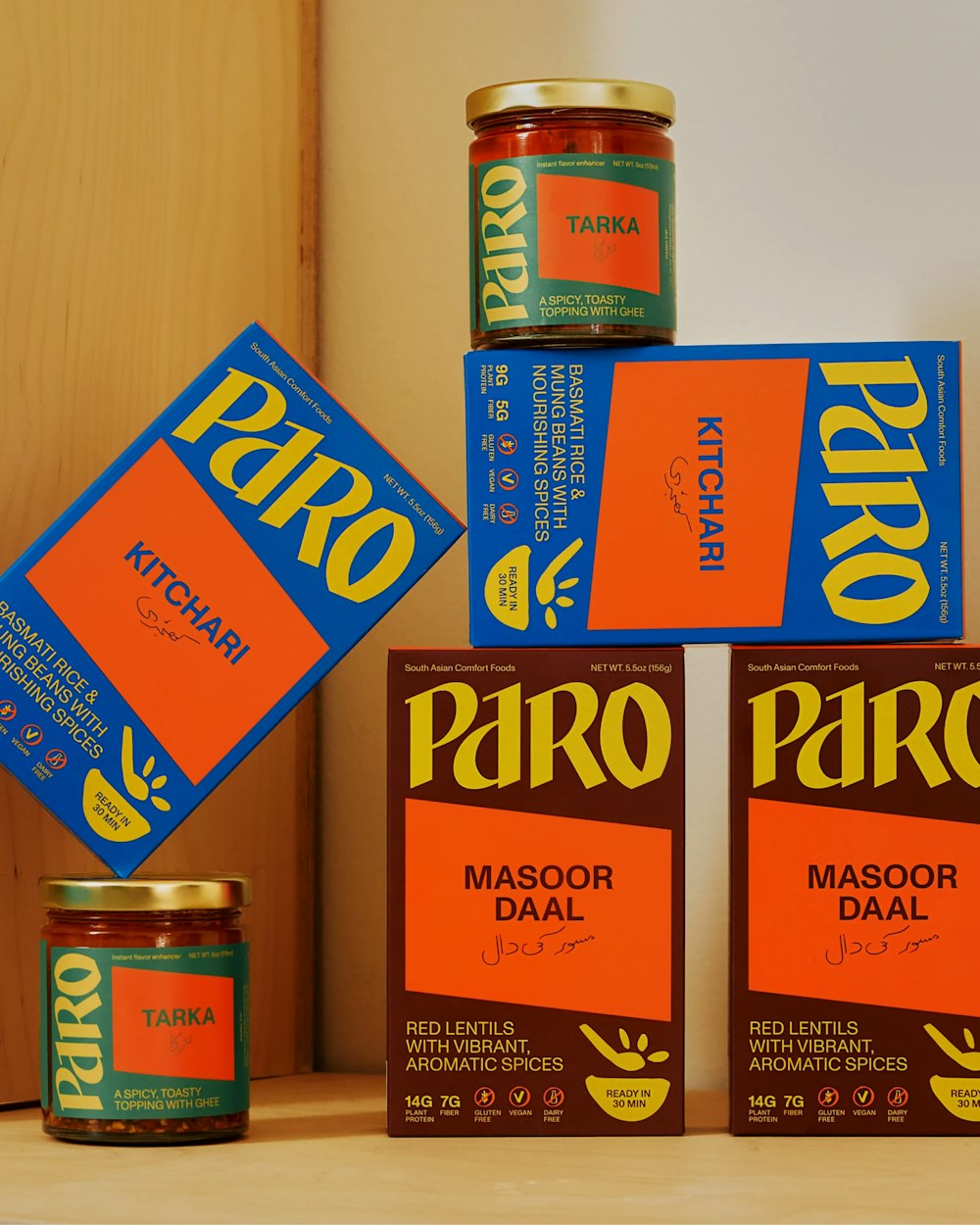 Paro packagings line up with Daal, Kitchari and Tarka Oil on a white and wood background.