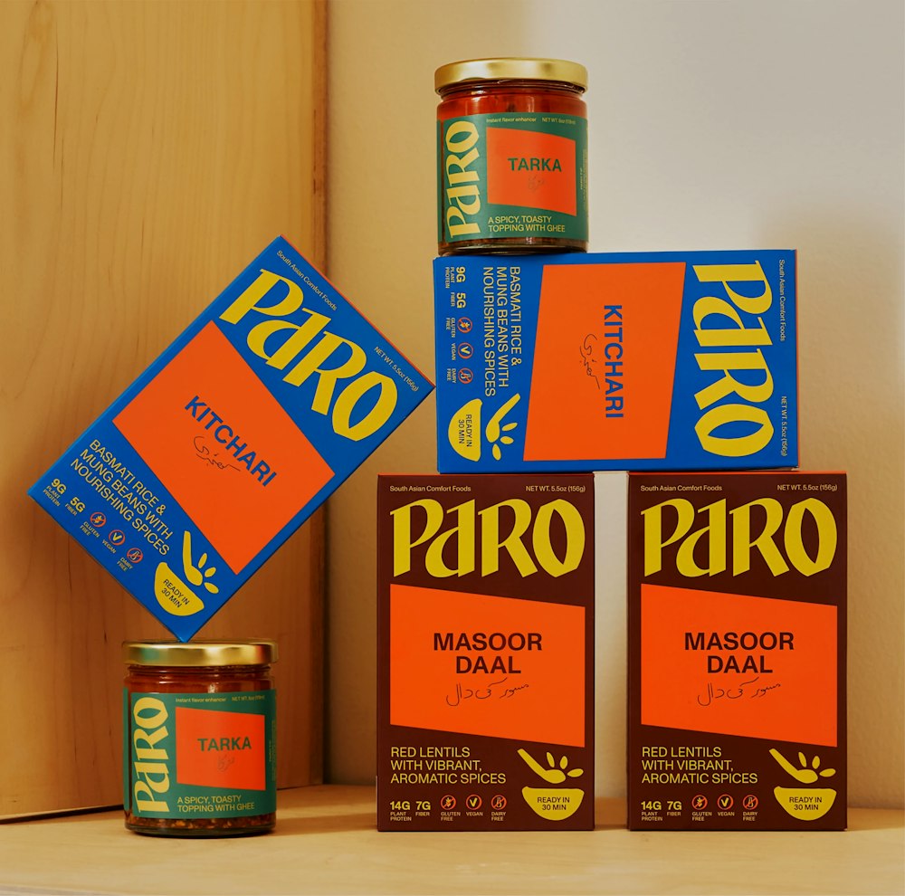 Paro packagings line up with Daal, Kitchari and Tarka Oil on a white and wood background.