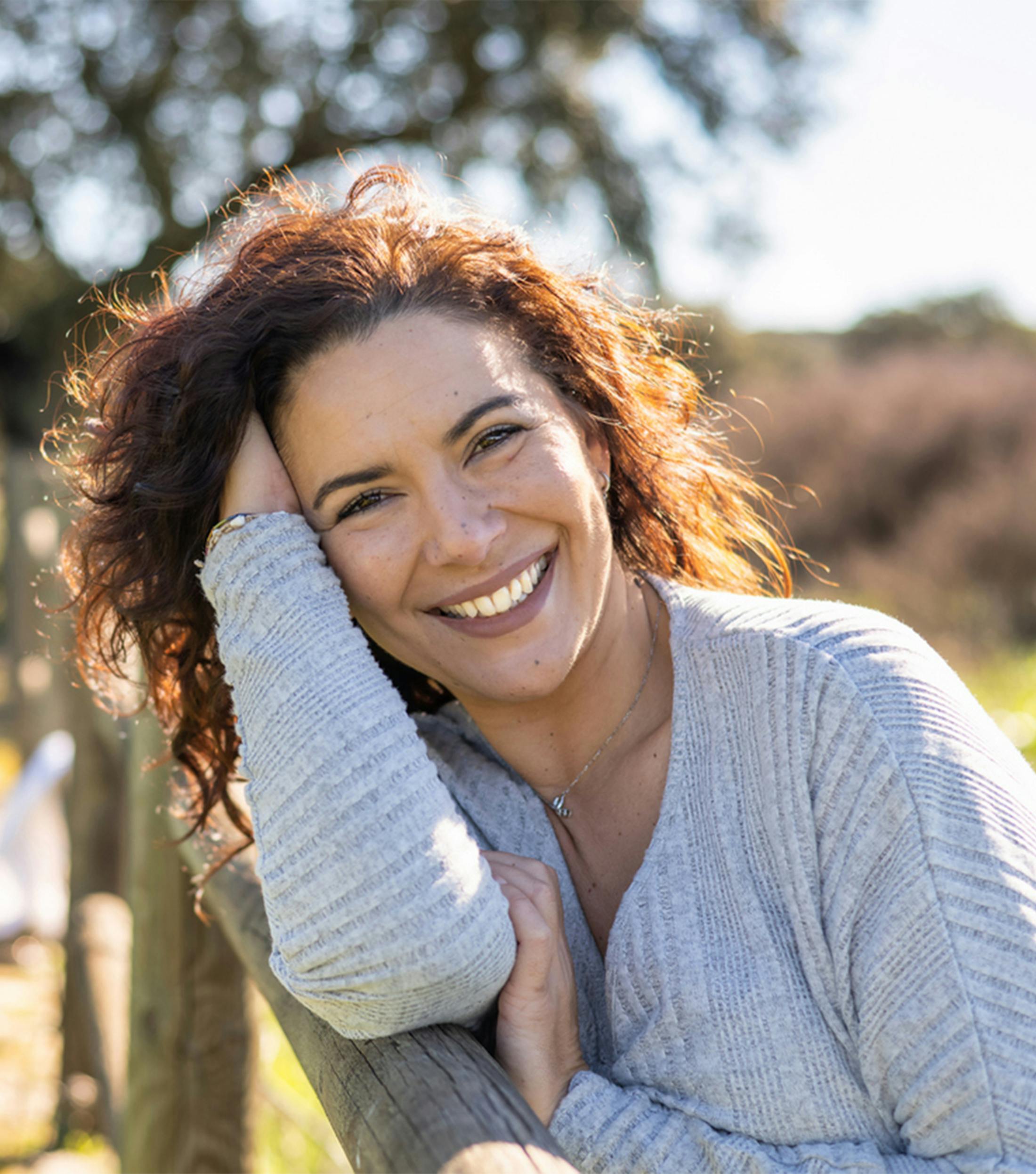 woman leaning against a wood post fence