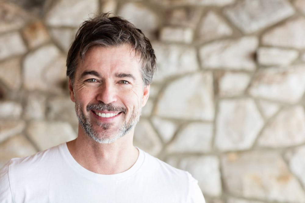 Smiling man with grey hair indicating successful PRP hair restoration therapy.