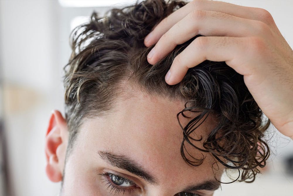 man looking at his hairline after getting growth factor therapy in Miami, FL