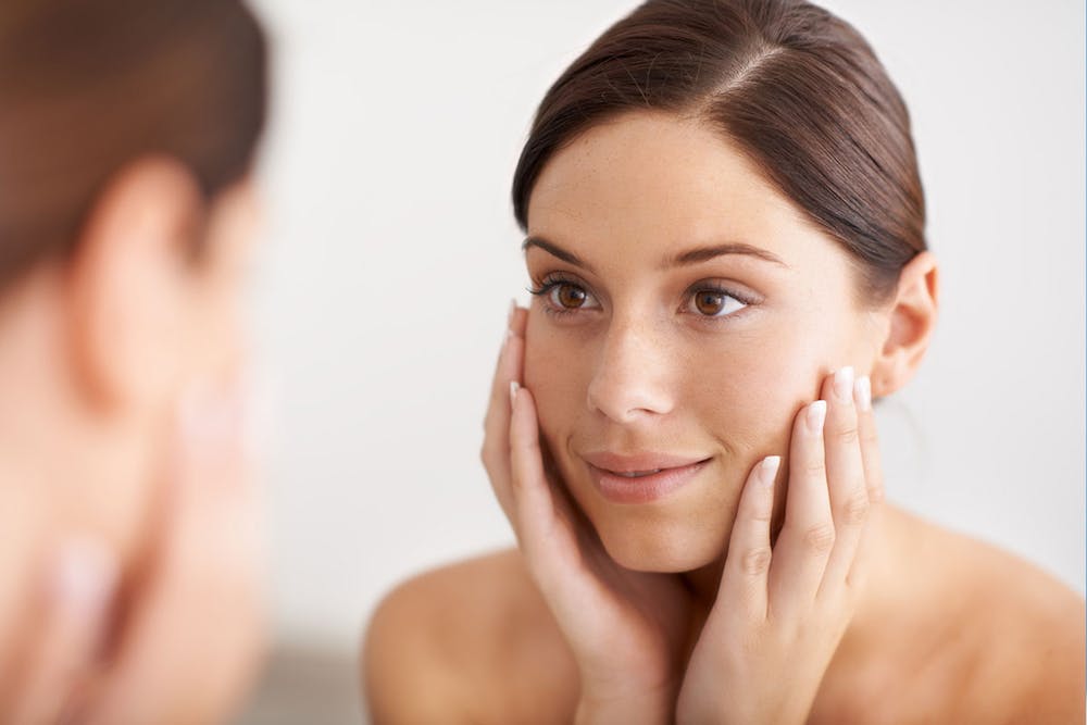 blog-when-do-rhinoplasty-results-start-to-show-2 woman looking in the mirror after her rhinoplasty in Miami, FL