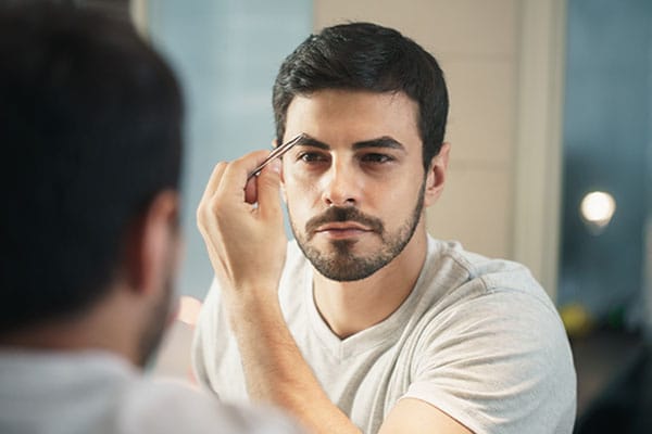 man looking in the mirror after his eyebrow transplantation in Miami, FL