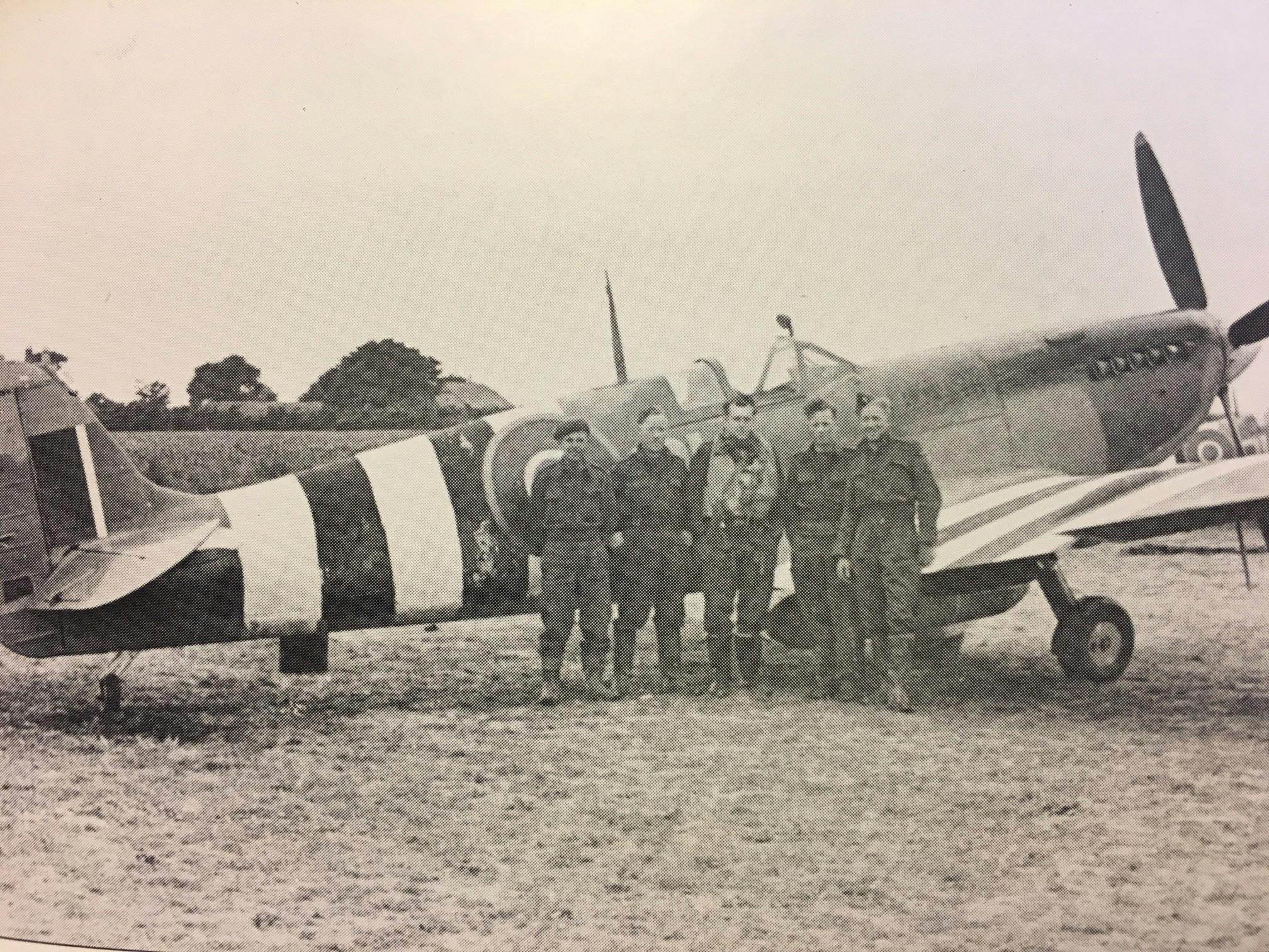 Image of the ALG Selsey airmen alongside a spitfire painted with black and white stripes across its wings and fusalage called Invasion Stripes to fend off friendly fire during the Normandy landings and D-Day 