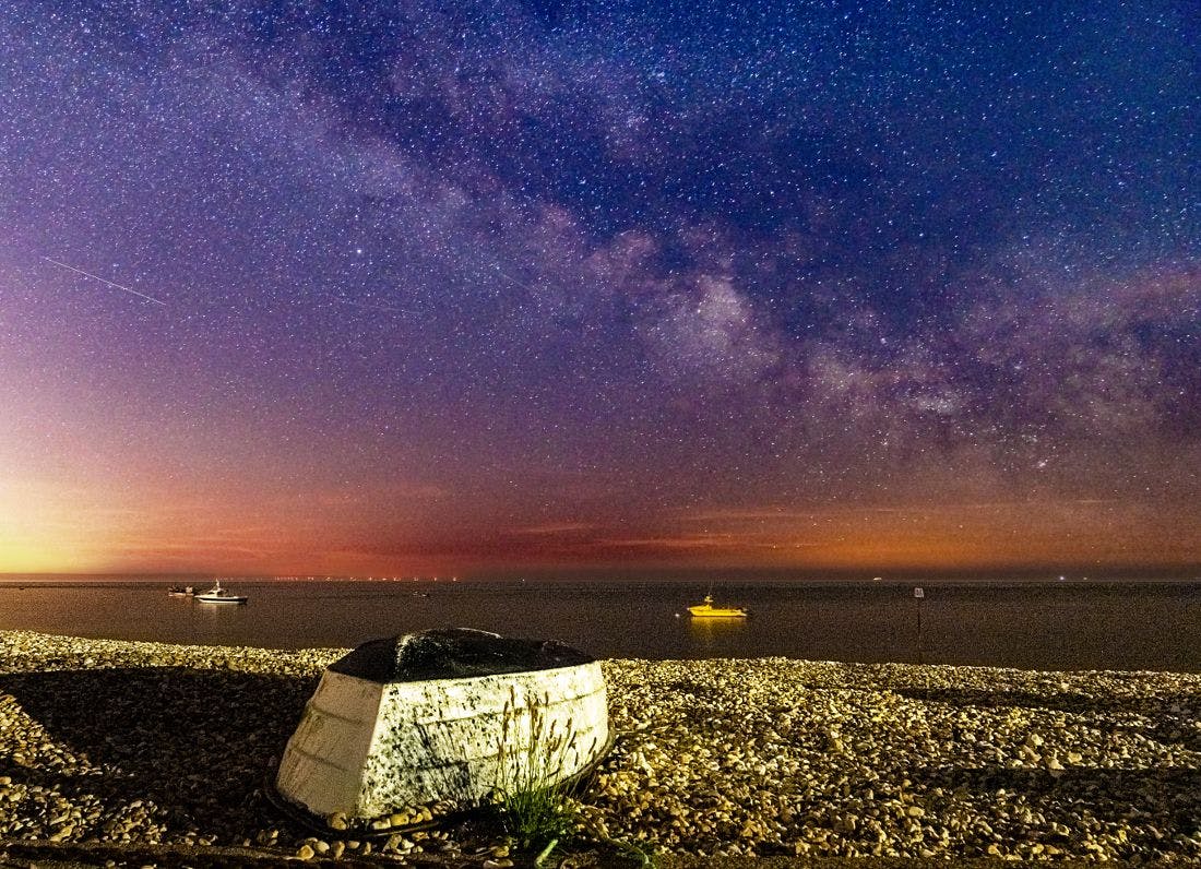 Milkyway captured over East Beach with a overturned boat on the shingle in the foreground