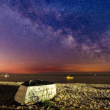 Milkyway captured over East Beach with a overturned boat on the shingle in the foreground