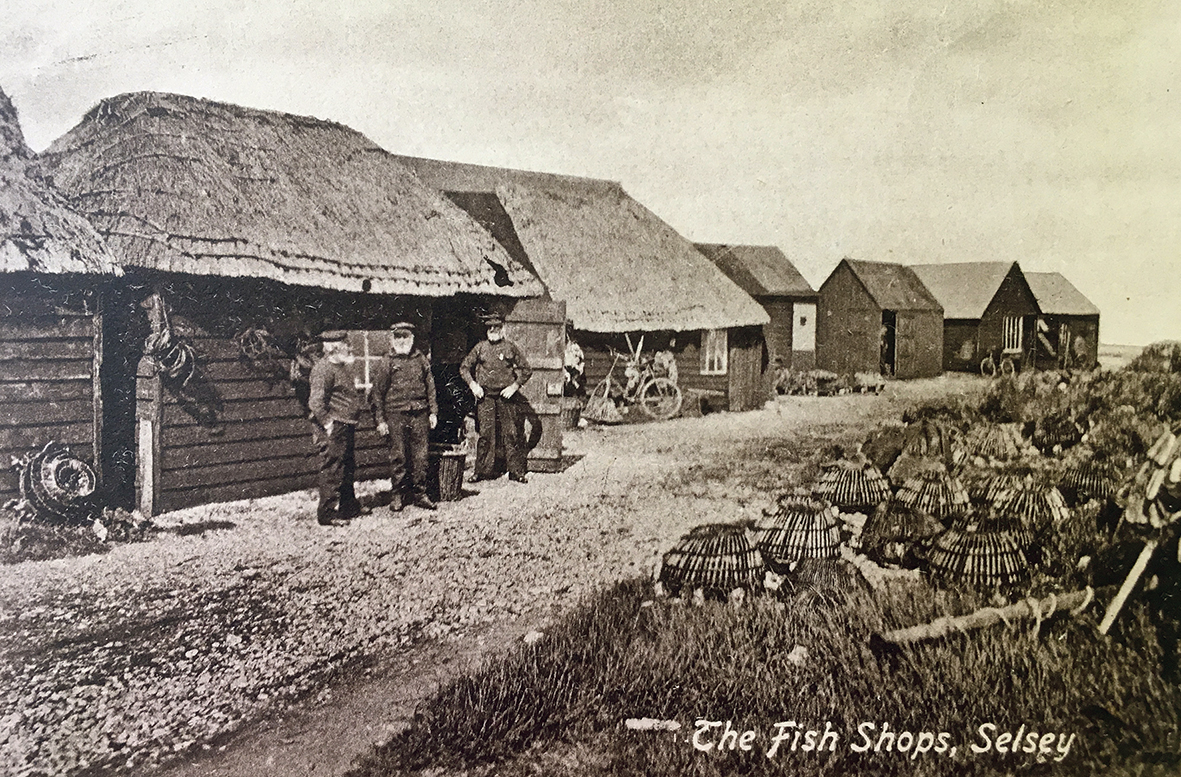 Three bearded Selsey Fishermen, outside their thatched fishing huts selling their produce.