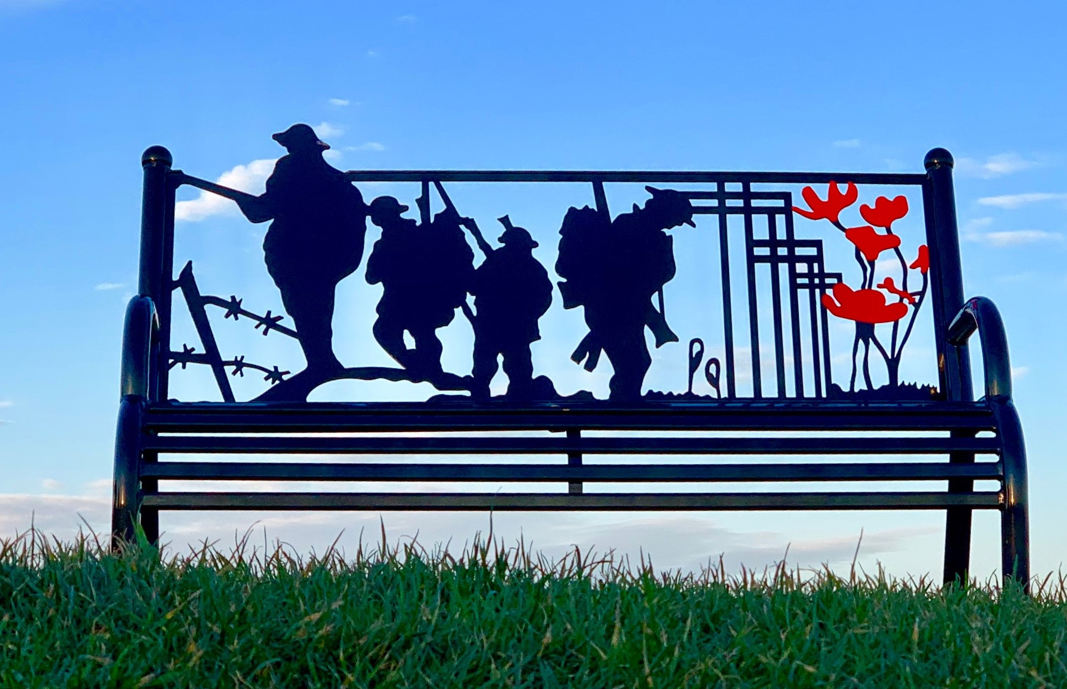 Oval Field Memorial Bench showing four servicemen and 6 poppies 