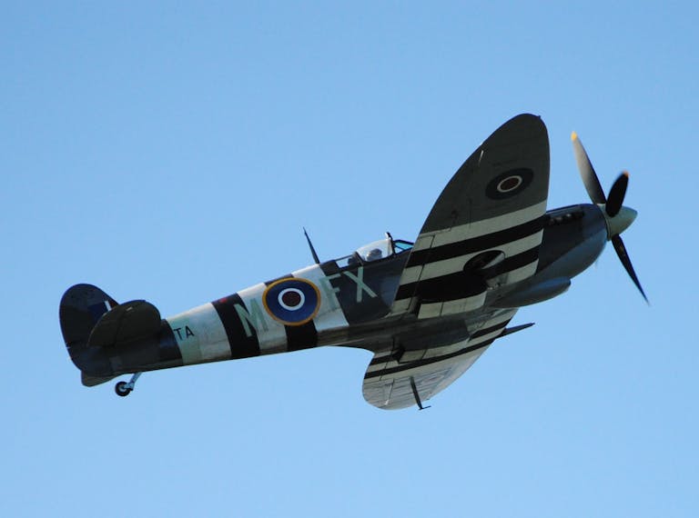 Colour image of a spitfire with black and white stripes, painted to protect against friendly fire during operation overlord