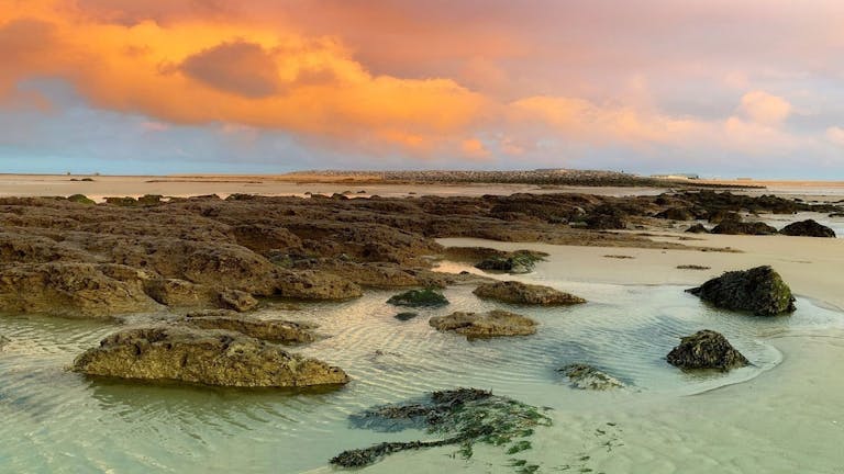 Clouds alight with the orange sun at suset over RSPB Medmerry Beach 