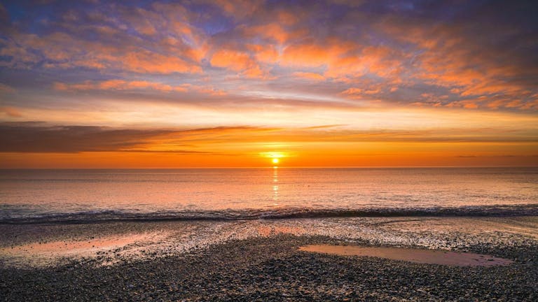 The sun rises over Pagham Harbour as the clouds radiate the light 