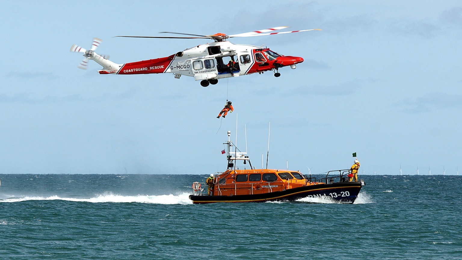 A coastguard helicopter hovers over the RNLI Selsey lifeboat as an individual is hoisted up to the helicopter.  This was part of the display during RNLI Selsey Lifeboat week.  