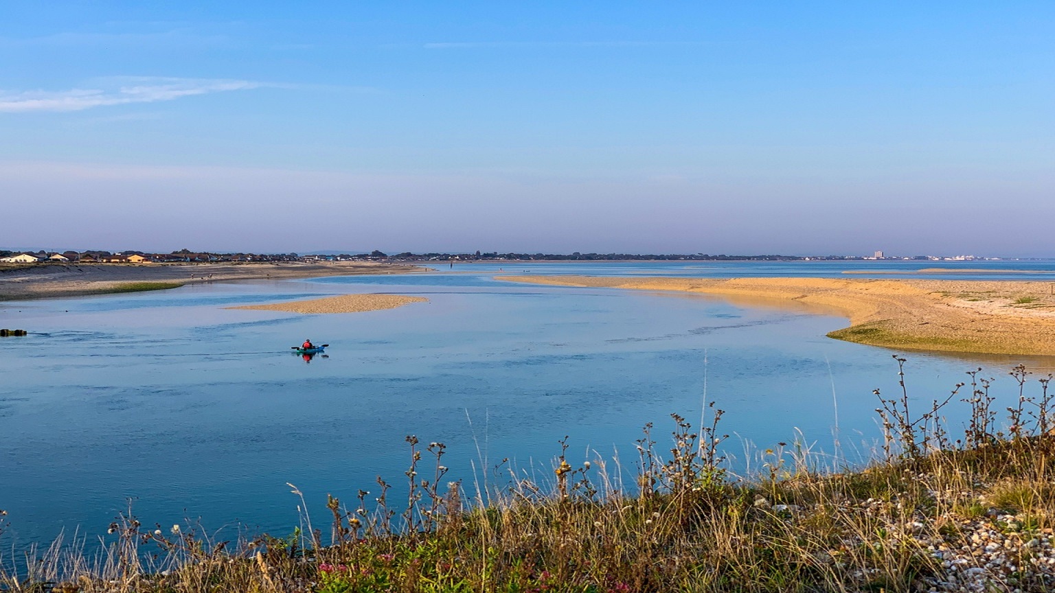 One kayaker in the sea at Pagaham Harbour with grass in the foreground