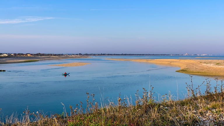 One kayaker in the sea at Pagaham Harbour with grass in the foreground