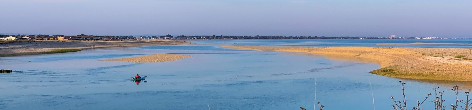 One kayaker in the sea at Pagaham Harbour with grass in the foreground