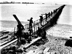 Men walking along the emergency pier for landing craft, courtesy IWM